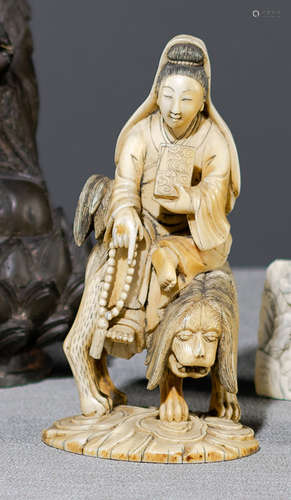 A CARVED IVORY MODEL OF GUANYIN SEATED ON A LION