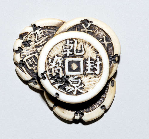 A CARVED IVORY NETSUKE OF FOUR COINS