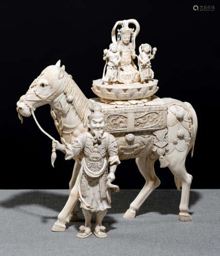 AN EXCELLENT CARVED IVORY OKIMONO OF A HORSE LED BY A GUARDIAN FIGURE CARRYING A TRIAD WITH KANNON AND TWO WORSHIPPERS