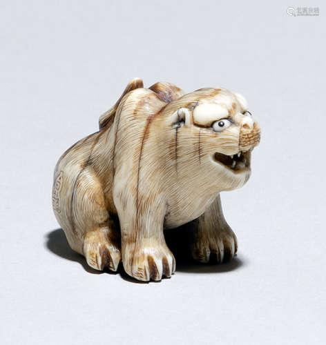 A CARVED IVORY NETSUKE OF A SEATED TIGER