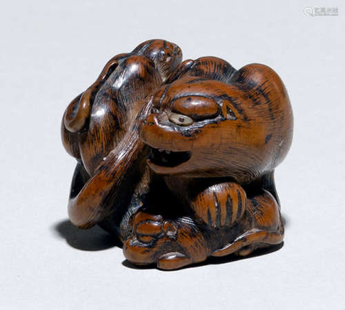 A CARVED WOOD NETSUKE OF A SEATED TIGER WITH CUB