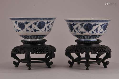 Pair of porcelain cups. China. 19th century. Decoration of stylized lotus scrolls in underglaze blue on a crackled white ground. Carved hardwood stands. Hsuan Te four-character mark on the base.  Bowl- 6