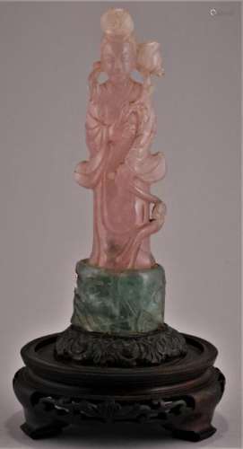 Rose Quartz carving. China. 20th century. Standing figure of Kuan Yin. Flourite and metal base set on a wooden stand. 5-1/2
