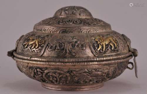 Silver box. Tibet. Early 20th century. Repousse decoration of Buddhist emblems. Round hinged form. Gilt accents.  4-1/4