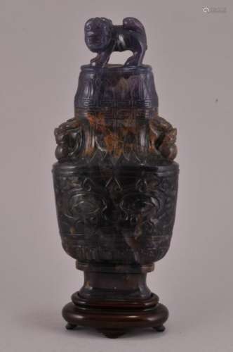 Hardstone covered jar. China. 19th century. Foo dog finial; and handles. Body decorated with Tao Tieh masks. Purple and brown agate.  Total height with stand- 7-3/4