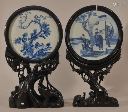 Two table screens. China. 19th century. Underglaze blue decorated plaques. One with figures, one with birds and flowers. Prunus carved hardwood stands.  Plaque 10