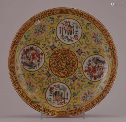 Porcelain plate. China. Kuang Hsu mark and probably of the period. Yellow ground with floral scrolls and reserves of dragons and phoenixes, the hundred antiques around a central shou character. Cafe au lait reverse with flowers. 9 3/4