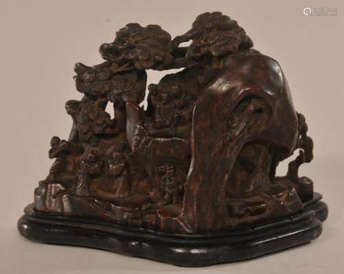 Agarwood carving. China. 19th century. Mountain landscape with a gathering of scholars. Fitted stand.   4 3/8