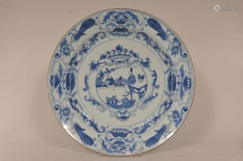 Porcelain charger. China. 17th century. Underglaze blue transitional style of a woman and child with armorial crest and floral borders. Edge register with four peacocks. 15 1/4