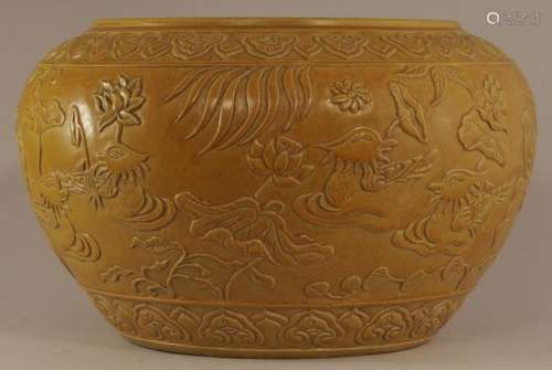 Stoneware bowl. China. Early 20th century. Begging bowl form. Surface carved with mandarin ducks and lotus plants. Mustard yellow glaze. 7