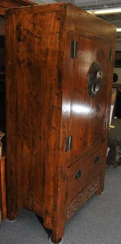 Elmwood cabinet. China 20th Century. Two cabinet doors over a single drawer. Apron carved with a Shou character and food dogs brass mounts. 80