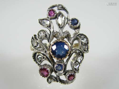 Ladies ring with diamond roses, sapphires and rubies - late 19th century, 750 yellow gold<br />/ silver, sculptural, floral ring head with a beautiful cornflower blue sapphire  in the center (ø ca.5 mm) surrounded by 11 diamond roses, 2 round faceted sapphires and 3 rubies, inner diameter: approx .17,6mm, ring head size: ca.27 x 19,2mm, weight: ca.7,18g