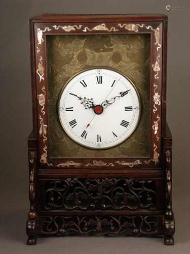 Table clock - China, 2-piece hardwood case, pearl inlay, open worked frame, glazed white<br />enamel dial, framed in reliefed and engraved brass plate with Chinese motifs of Fo dogs between tendrils, clockwork with engraved brass plate, quarter hour strike on 2 Bells, drive via chain / worm, spindle gear, 8-day running time, transport locking of the pendulum, slight signs of age or wear, HxWxD: approx. 40x26.5x21cm