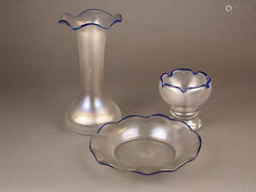 Konvolut Eisch Perlmuttglas - Erwin Eisch, Frauenau, irisierendes Perlmuttglas, gewellte<br />blaue Ränder, verschliffener Abriss, 3-tlg.: 1x Vase, H.ca.25cm, 1x Fußschale, Unterseite signiert, mit Original-Klebeetikett Perlmuttglas, H.ca.12cm, 1x Schale, Unterseite signiert, HxD:ca.4x22cm, Gebrauchsspuren, Ränder stellenweise berieben