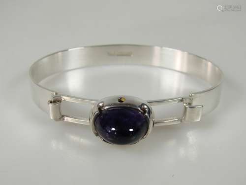 Designerarmreif mit Amethyst - Finnland, 1970er Jahre, 925er Silber, ovaler Klappreif mit<br />geometrisch durchbrochener Mitte und Steincabochon (13,2 x 9,5 mm) in Zargenfassung, Innenmaß: ca.62 x 49 mm, Breite: ca.8 mm, Gewicht: 18,7 g, Gepunzt: 830 / Finland