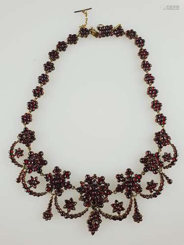 Granatcollier - filigran gearbeitet, besetzt mit facettierten Granaten, blüten- und<br />sternförmige Elemente, mittig festonartige Abhängungen, Kastenverschluss mit Sicherheitskette, Alters- bzw. Gebrauchsspuren, im alten Box 