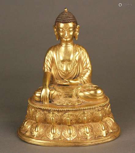 Buddha Shakyamuni - Sinotibetan, probably 19th century, gilt copper alloy, seated on a<br />double lotus throne, the right hand in the bhumisparsa mudra -the gesture of touching the earth or calling the earth to witness the truth, the left hand resting in his lap, the ornamented garment's borders and the lotus leaves on the pedestal engraved, height c.20 cm