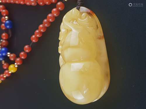 Amber Amulet - China, very fine carving in the form of a double gourd with voluted<br />tendrils, elaborated as a high relief, in China the gourd is considered as a symbol of fortune, because the legendary Xian (Daoist immortals) carried their longlife elixirs  in such belt-mounted vessels, amber ca.5x2,7cm, on chain with jasper beads, in between bright amber beads and discs, total length: ca.60cm