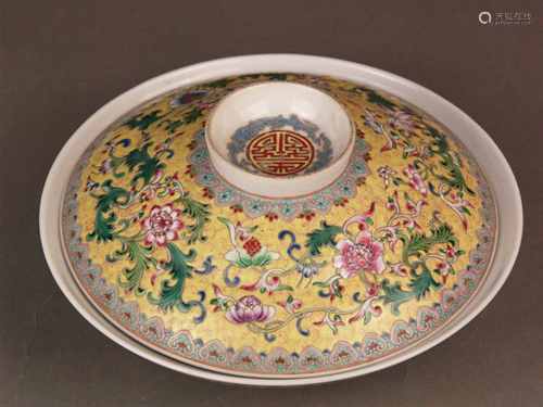 Famille Rose Lidded Bowl - porcelain, decorated with various leafy flower tendrils and<br />horizontal ornamental borders with Ruyi patterns on yellow background, high ring-shaped knob / stand with Shou medallion, bottom surface with red retrospective four-character mark ''Qianlong nian zhi '', H.ca.10cm / dm. (Bowl) at the bottom ca.20,5cm