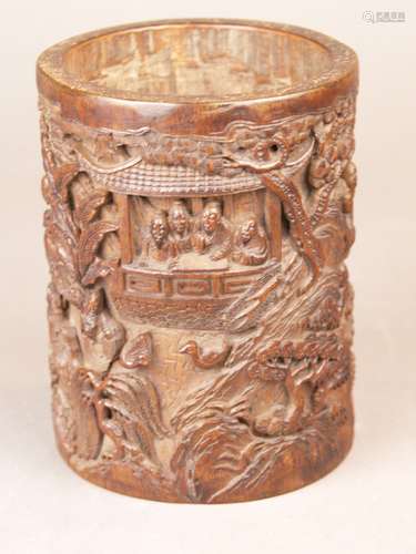 Brush holder - China 19th century, bamboo elaborately carved and brownished, cylindrical<br />body with extensive detailed high relief carving with tree-covered landscapes (pines, bamboo, palm trees), pavilions and figures staffage, figurative scene in landscape, 4-character mark, H. ca.15cm / ca.11.5 dm.