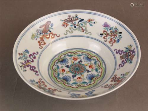 A doucai 'anbaxian' ogee dish - China, porcelain brightly enamelled,with deep rounded<br />sides rising from a tapered foot, the interior of the dish is decorated with a central swirled medallion surrounded by peaches and demi-flowerheads interspersed with lotus scroll, the cavetto with beribonned  Eight Daoist Emblems ''anbaxian'', the exterior is painted with stylised blooms and foliate scrolls above a colourful ruyi-head border around the foot, blue Qianlong seal mark to the base, c.5,5 cm high/c.20,3cm Dm.