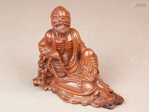 Figurine of a Luohan with prayer beads - China, boxwood fine cut, sitting in a relaxed<br />posture with angled left leg, h. / B.ca.12x14 cm, wood with cracks, partly restored