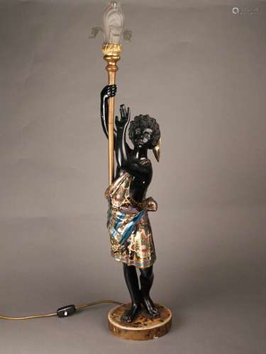 Figurative Torchère in Venetian style - Italy, early 20th century, carved wood, partly<br />wood mass, polychrome painted, lacquered, a figure dressed with an antique patterned tunic and Phrygian cap standing on a round base, on the right shoulder with torch-like lamp holder, Art Nouveau - Glass shade in the shape of an iris flower in leaf-shaped brass frame, electrified, with old cable switch, working condition, H.ca.92,5cm, signs of age and wear, small color split, right hand with continuous crack