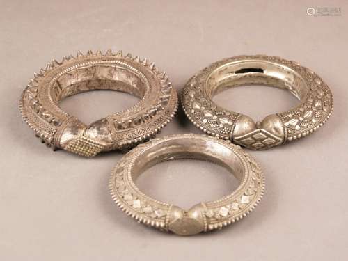 Three antique nomad silver bangles - Yemen, metal alloys with silver content, elaborate<br />appliqués, different designs, hollow worked, signs of age and use, damages, D. (outside) ca.11 / 12 / 12,5cm, together ca.435g