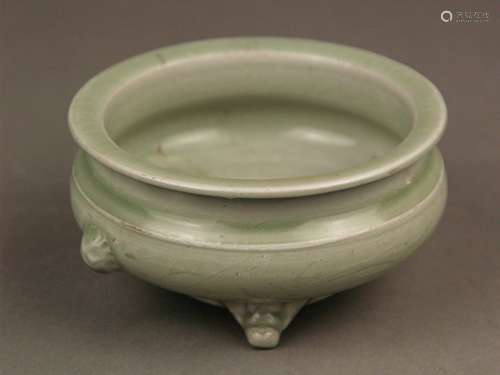 Celadon Incense Burner - Longquan, China, possibly late Ming Dynasty (1368-1644),<br />stoneware with crackled seladongreen glaze, reddish burned stoneware partly exposed inside and on the underside, half round lion's heads as handles, cylindrical neck ring with flared rim, on three stylized mask feet, Dm (rim) ca.11,5 cm / h.ca.6cm