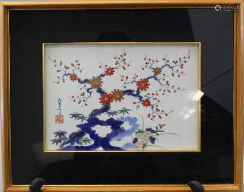 A framed Japanese porcelain plaque with tree and flowers decorations.