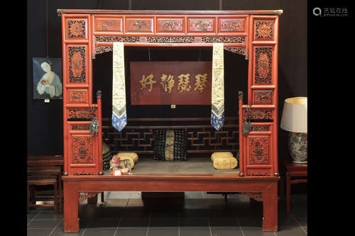 antique Chinese Qing-period (completely restored) bed in lacquered and sculpted wood – with it iron curtainholders and typical (bed) textile