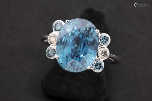 rare natural zircon of more then 10 carat and with a superb color, set in a ring in white gold (18 carat) with ca 0,50 carat of white and fancy blue high quality brilliant cut diamonds