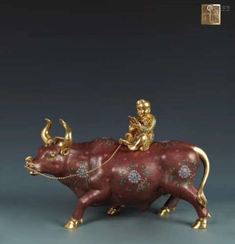 A CLOISONNE COW AND BOY SHAPED ORNAMENT