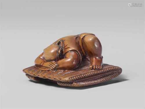 A boxwood netsuke of a sleeping peasant. Mid-19th centuryCrouching on a folded straw mat, the head