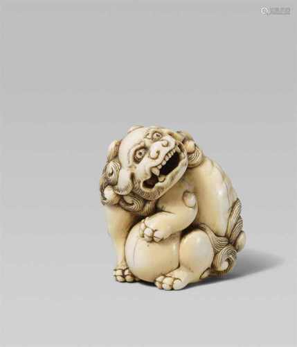 An ivory netsuke of a mighty shishi. Early 19th centurySeated on its haunches, the head tilted and