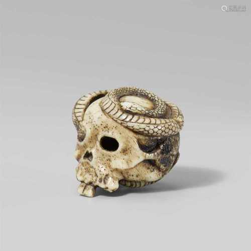 A macabre bone netsuke of a skull and a snake. Late 19th centuryA long slender snake winds through