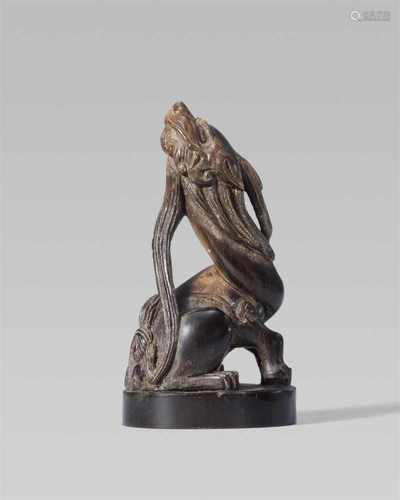 A nearly black horn seal netsuke of a kirin. 19th centurySeated on its haunches, neck twisted and