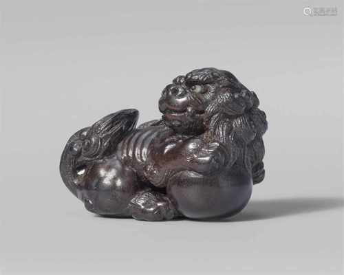 A fine very small Tsu school ebony netsuke of a shishi, by Tômin. Mid-19th centurySeated, the head