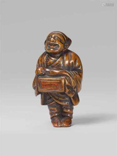 A boxwood netsuke of a street puppeteer. 19th centuryStanding with a wooden box hanging from his