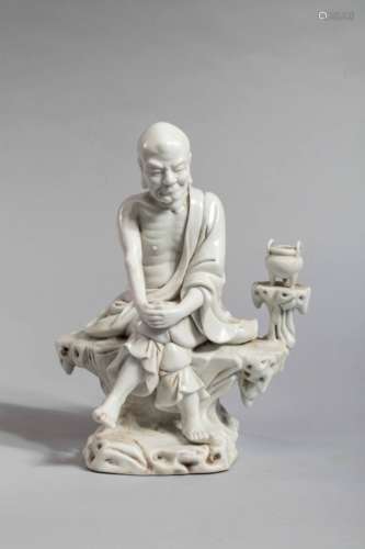 Lohan figuré   assis sur une souche de bois, le corps d'ascète décharné couvert d'un textile monastique ,   un brûle parfum près de lui. Porcelaine blanc de   chine de Dehua. Province du Fujuan. Chine. HT 23,5cm x L 20cm.