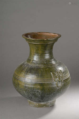 Vase de forme Hu rappelant la vaisselle   rituelle de bronze en terre cuite moulée de   lignes horizontales et anses latérales à masque de Tao Tié sous glaçure monochrome   vert plombifère. Chine. Dynastie Han. 206 avant à 220 après JC. Ht 37cm x diam 30cm.