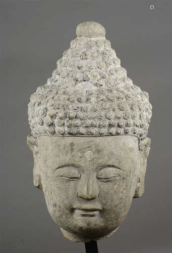 Tête de Buddha à la coiffure bouclée surmontée de l’ushnisha   serti de deux joyaux Urna au centre des bouclettes et au milieu du front.   Pierre grise. Chine. Dynastie Yuan. 14 ème siècle . 65cm.