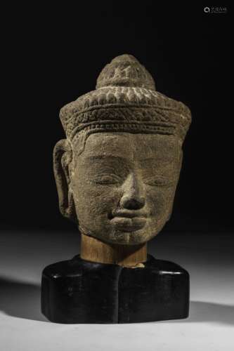 Tête de Shiva coiffée   d'un diadème retenu par un lien noué au verso à la coiffure bouclée surmonté d'un chignon d'ascète. Pierre grès beige à patine du temps. Khmer. Cambodge. Bayon. 13 ème siècle. Ancienne collection Française.