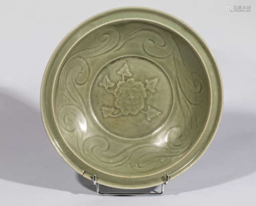 Plat du Longquan en épaisse    porcelaine décorée en   incision sous couverte monochrome céladon d’une frise de rinceaux au Marli et d’une   pivoine épanouis au centre . Chine. Dynastie Yuan.   1279 à 1344. Diam 33,5cm. Test de thermoluminescence   confirmant la datation. Petit défaut de cuisson au   marli.