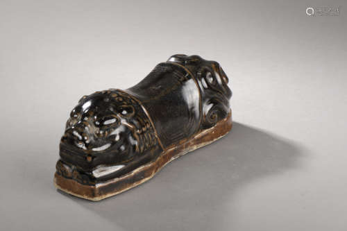 Repose tête zoomorphe illustré d'un chien de fô couché la queue en panache harnaché d'une selle   en grès porcelaineux à   couverte monochrome brune. Chine. Dynastie Yuan. 1271 à 1368. 27x ht 10,5cm.Test de thermoluminescence.