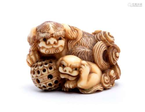 A HORN INLAID IVORY NETSUKE OF A SHISHI WITH BALL ...