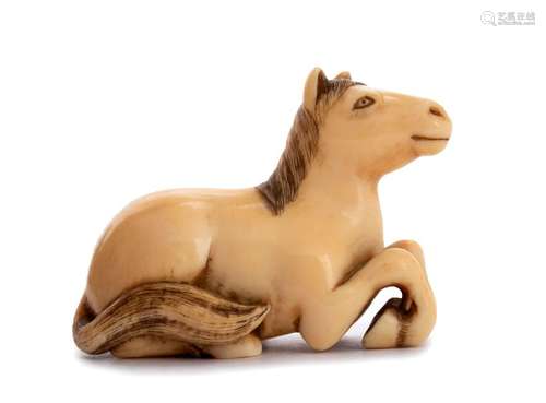 AN IVORY NETSUKE OF A RECUMBENT HORSE 19th century...