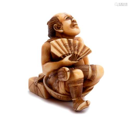 AN IVORY NETSUKE OF A SEATED MAN WITH FOLDING FAN ...