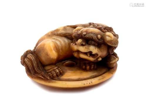 A MARINE IVORY NETSUKE OF A SHISHI ON A DISC 19th ...