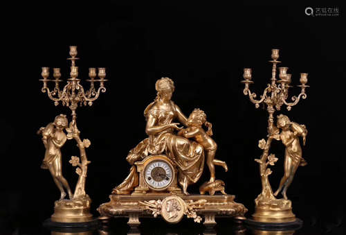 A GILT BRONZE FIGURE SHAPED CLOCK WITH CANDLESTICK